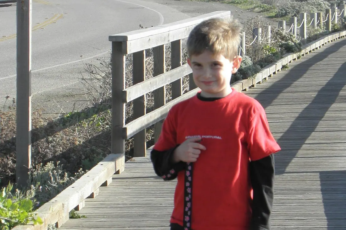 A Bollinger boy walking his dog on a boardwalk.