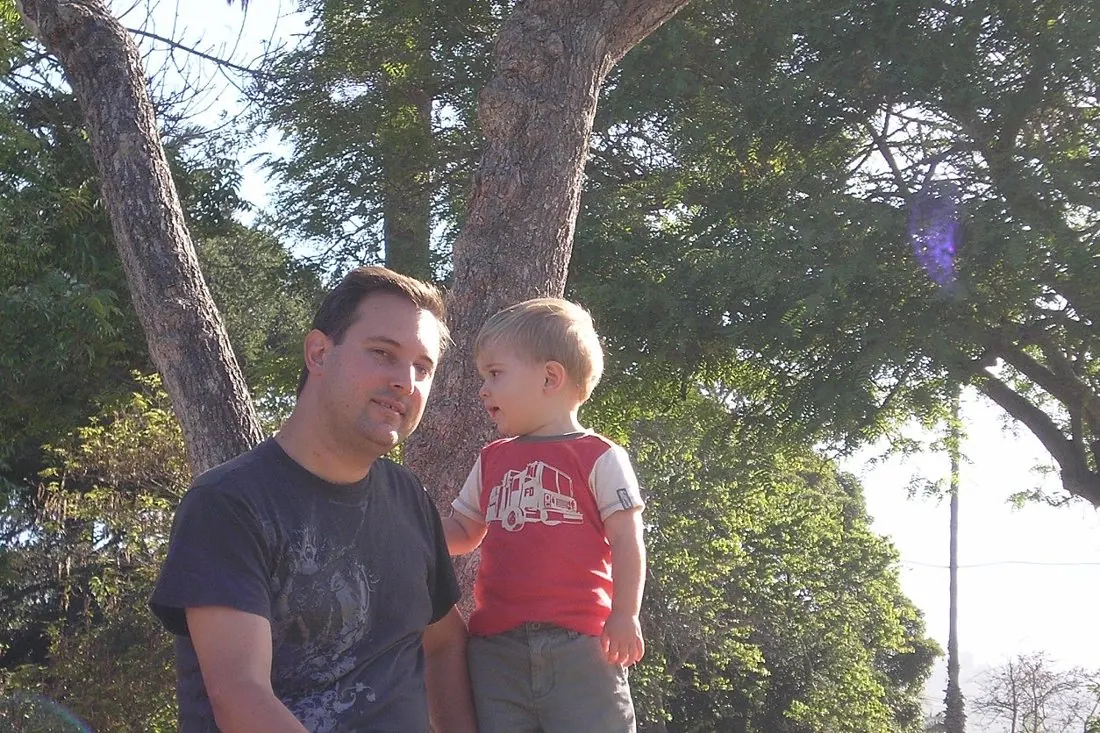 A Bollinger father and son sitting together under a tree.