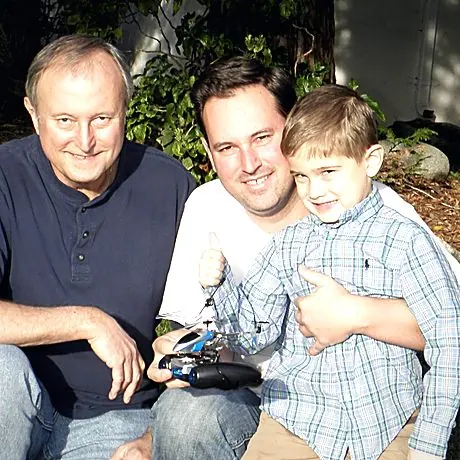 Grandfather, father and son in a garden.